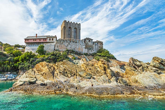 The fortified arsanas (sea-gate tower) of the Great Lavra monastery rising above the rocks on the Athos peninsula.